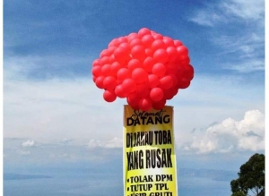 Spanduk bertuliskan “Selamat Datang di Danau Toba, Danau Indah Penuh Masalah Kerusakan Lingkungan” terbang di atas Danau Toba, Sabtu, 25 Februari 2023. (Foto: Dok)